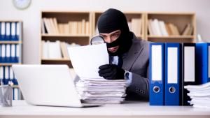 Theft in ski mask looking at files with magnifying glass